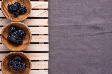 Ahşap kaselerin sınırında, üzerinde böğürtlen olan küçük tahta sandıkların üzerinde keten bir bezin üzerinde oturuyorlar.