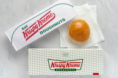 Flourtown, PA - 15 Mayıs 2024: Krispy Kreme kutusu ve kağıt şapkalı kağıt peçeteli çörek.
