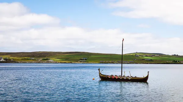 Lerwick, Shetland - 12 Temmuz 2024: Lerwick açıklarında suda oturan Dim-Riv adlı bir Viking teknesindeki Bressay Adası 'na bakıyorum..