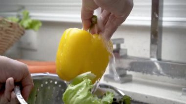 Ev mutfağında sarı biber yıkayan eller, yavaş çekim video.