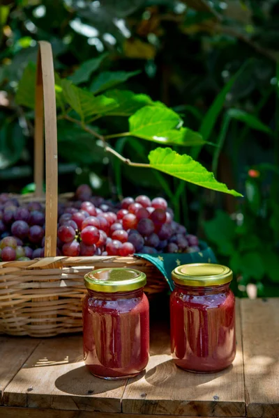 漂亮的篮子里装满了新鲜的葡萄 前面有2罐葡萄果酱 没有拉贝的罐子 — 图库照片