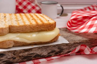 Peynirli somun ekmekli sandviç, açık ahşap masa, ince pas.