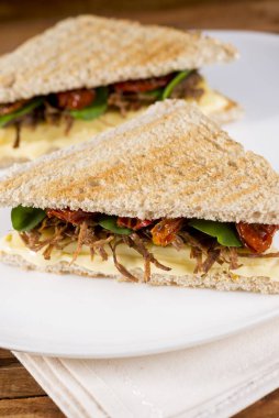 Etli ekmek sandviçi, tartışmalı, kurutulmuş domates ve peynirli.