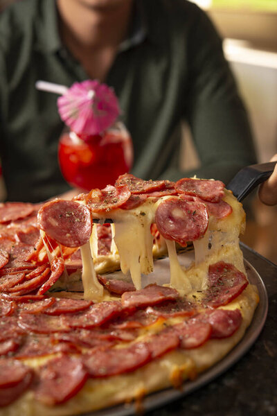 slice of salami pizza being pulled and cheese stretching