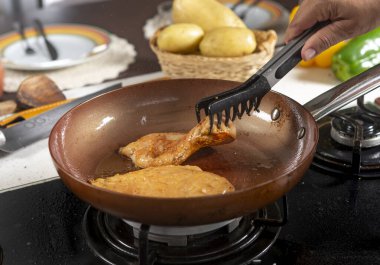 Şef, restoranın mutfağında tavuklu biftek pişiriyor.