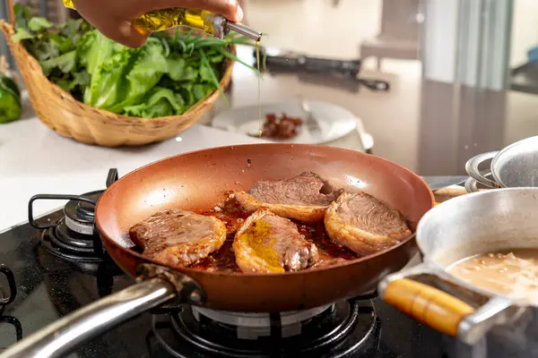 Şef, restoranın mutfağında tavada biftek pişiriyor.
