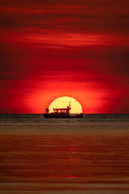 Sailing boat against the dramatic sunset at Mindil Beach, Darwin. clipart