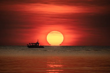 Sailing boat against the dramatic sunset at Mindil Beach, Darwin. clipart