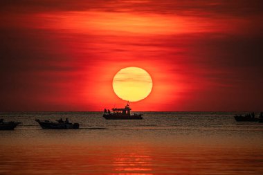 Sailing boats against the dramatic sunset at Mindil Beach, Darwin. clipart