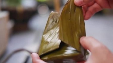 Kapalı Asyalı kadın eli muz yaprağıyla doldurulmuş hindistan cevizli krema yiyor. Ev yapımı Tayland tatlısı.