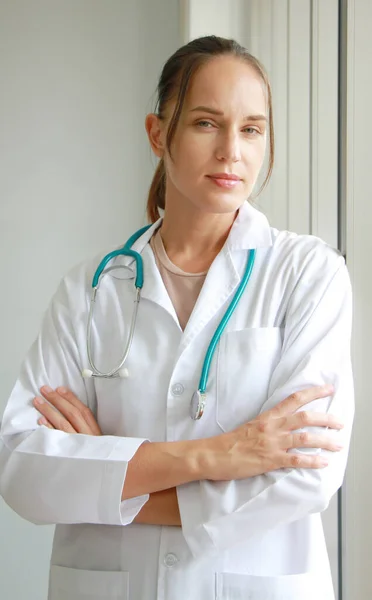 Professional Caucasian doctor woman in Gown uniform with stethoscope is standing and smiling portrait near glass wall in hospital and clinic center