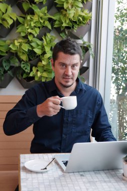 Kafkas işadamı kafeteryada bir fincan kahve içiyor. İş ve internet ve dizüstü bilgisayar ticareti konusunda ciddi görünüyor. Küçük işletme konsepti için başla