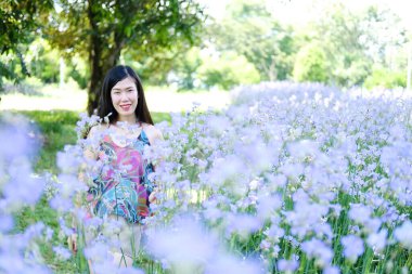 Güzel Asyalı kadın gülümsüyor ve gevşiyor Mor Murdannia Giganteum çiçek tarlasında