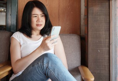 Akıllı telefondan sosyal medya platformunda online alışveriş arayan Asyalı iş kadını