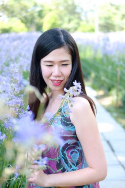 Güzel Asyalı kadın gülümsüyor ve gevşiyor Mor Murdannia Giganteum çiçek tarlasında