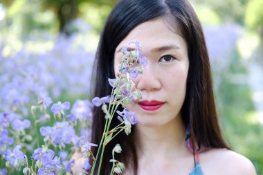 Güzel Asyalı kadın gülümsüyor ve gevşiyor Mor Murdannia Giganteum çiçek tarlasında