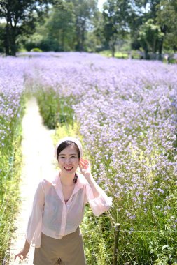 Güzel Asyalı kadın gülümsüyor ve gevşiyor Mor Murdannia Giganteum çiçek tarlasında