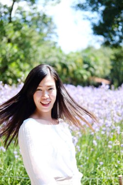 Güzel Asyalı kadın gülümsüyor ve gevşiyor Mor Murdannia Giganteum çiçek tarlasında