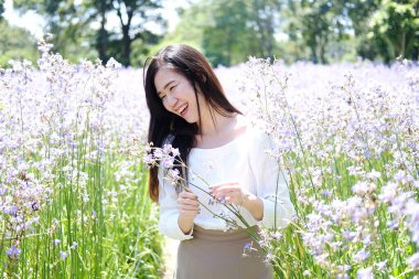 Güzel Asyalı kadın gülümsüyor ve gevşiyor Mor Murdannia Giganteum çiçek tarlasında