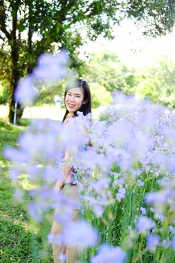 Güzel Asyalı kadın gülümsüyor ve gevşiyor Mor Murdannia Giganteum çiçek tarlasında