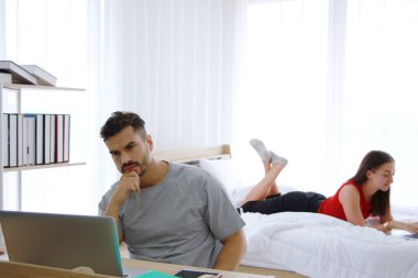 Ciddi bir beyaz adam ve karısı yatak odasında sosyal medya teknolojisinde online alışveriş işiyle birlikte çalışıyorlar. İşadamı işyerinde stresli ve endişeli