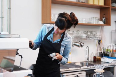 Kafede kahve makinesiyle kahve yaptığı için elinde kahve fincanı tutan gülümseyen beyaz kadın. İş kurma kavramı