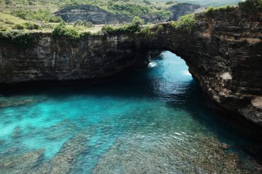 Dalgaların manzarası Endonezya 'nın Bali adasındaki kırık plajlarda mavi sakin deniz ve varış noktasında kayalık kayalıklara ve vahşi dağa çarpıyor.