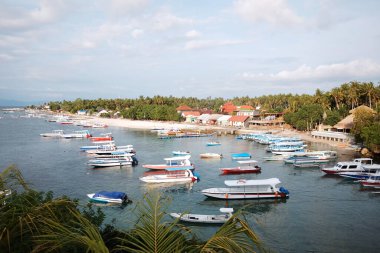 Bali, Endonezya - 12 Haziran 2018: Güzel balıkçı tekneleri manzarası ve turist hız tekneleri kıyıdaki rıhtımda bulut ve gökyüzü ile Bali adasındaki deniz plajı