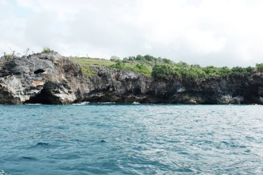 Kayalık kayalıklardaki mağara manzarası. Denizde köpük dalgaları ve su sıçraması. Seyahat hedefi Endonezya 'daki Bali' de yaz denizi sakin