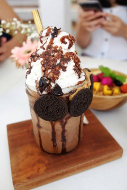 Ev yapımı taze çikolatalı milkshake, kremalı ve karamelli ahşap tabakta.