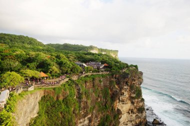Bali, Endonezya - 10 Aralık 2018: Suluban sahilindeki Pura Luhur Uluwatu tapınağının altında kayalık kıyı ve okyanus dalgaları olan sahil uçurumu veya Bali 'deki mavi nokta