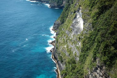 Deniz kenarındaki kayalık kayalıklarda köpük dalgaları ve su sıçratan mağaranın güzel hava manzarası. Seyahat hedefi Endonezya 'daki Bali' de yaz denizi sakin