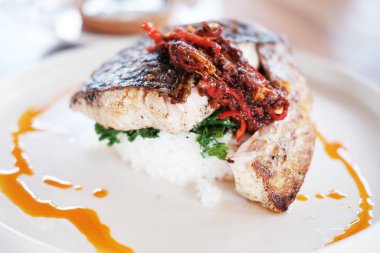 Geleneksel yiyecek, bol yağda kızartılmış balık, beyaz tabakta pilav ve kırmızı biber sosu.