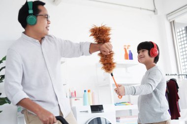 Gülümseyen Asyalı baba küçük oğluyla oynuyor. Tatilde çamaşırhanede temizlik ve yıkanma için. Aile aktiviteleri ve evde eğitim için çocuk eğitimi