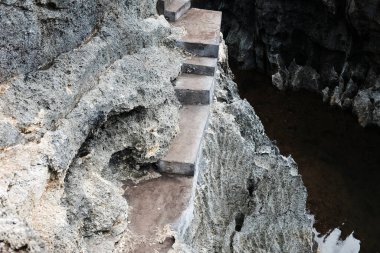 Kayalık kayalıklarda yürümek için eski beton merdivenler ve Endonezya 'nın Bali ve Nehrinde büyük taş dağ