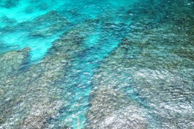 Hava manzarası berrak mavi deniz yüzeyi ve sualtı kayaları yazın doğal güneşli.