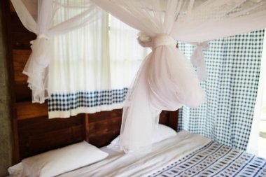 Tayland 'da ahşap konaklama odasının yatak odasındaki yatak çerçevesinde asılı sivrisinek ağı.