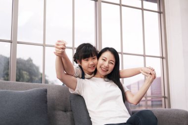 Asyalı kız, kanepede oynuyor. Aile sıcak bir evde birlikte mutludur. 