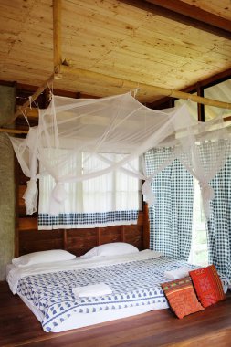 Tayland 'da geleneksel ahşap evde kalma geleneğinin yatak odasındaki yatak çerçevesinin etrafında asılı sivrisinek ağı.
