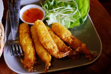 Sebzeli taze kızarmış karides ve beyaz tabakta sos.