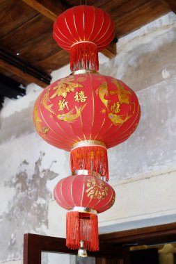 Çin 'de yeni yıl tatilinde doğal güneş ışığı altında ahşap tavanda asılı Çin karakterleri olan güzel kırmızı Çin kağıt feneri.