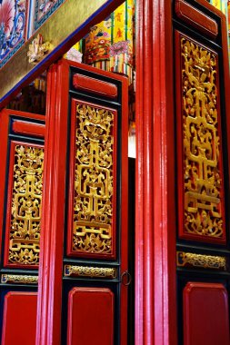 Tayland 'da Çin kültürü tanrılarına tapınma ve hürmet için ahşap kırmızı kapı üzerinde güzel altın şablon işi.