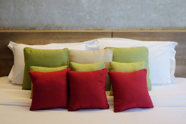 Beyaz yatağa döşenmiş yeşil ve kırmızı sırt yastığı