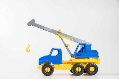 Plastik araba. Oyuncak modeli beyaz arka planda izole edilmiş. Yükünü kaldırmak için ok taşıyan sarı-mavi bir vinç..