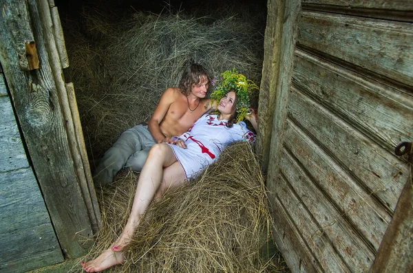 A couple in love in the hayloft of an old wooden barn.