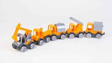 Construction vehicles lined up in a row. Multi-colored children's toys plastic trucks on a white background.