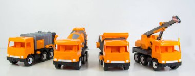 Construction vehicles lined up in a row. Multi-colored children's toys plastic trucks on a white background.