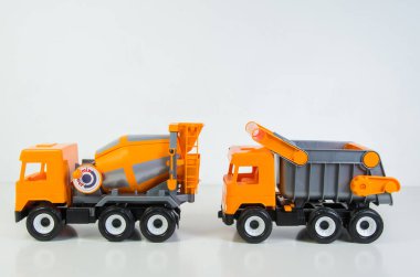 Construction vehicles lined up in a row. Multi-colored children's toys plastic trucks on a white background.