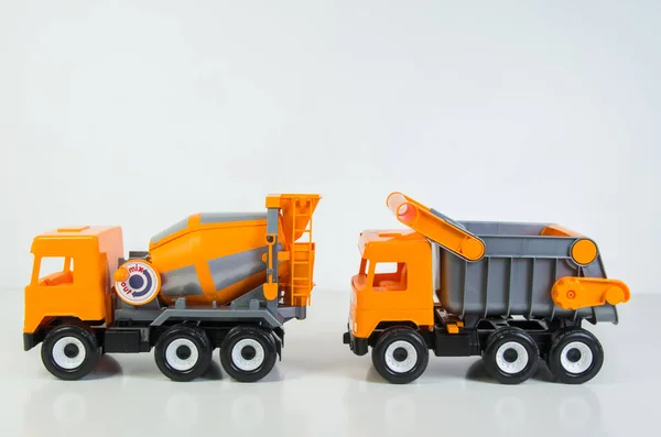 Construction vehicles lined up in a row. Multi-colored children\'s toys plastic trucks on a white background.