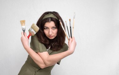Tulumlu kadın ressam beyaz arka planda resim yapmak için fırça kullanıyor..